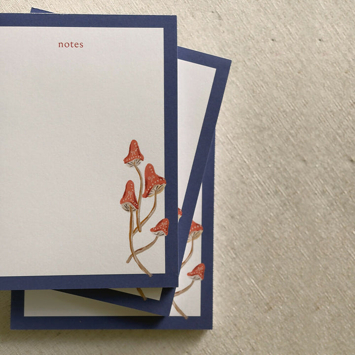 hand painted red cap mushrooms with a dark blue border desk notepad