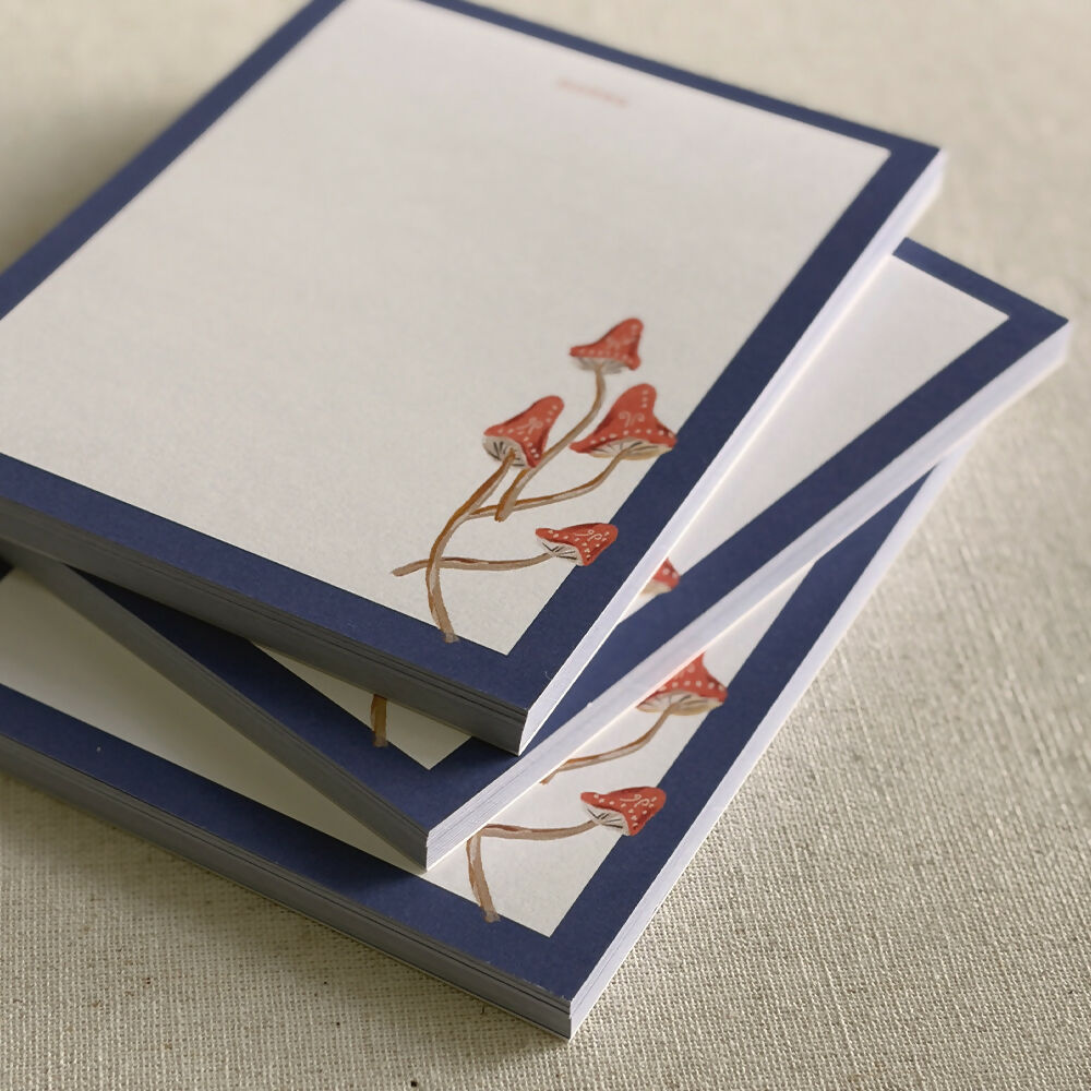 hand painted red cap mushrooms with a dark blue border desk notepad
